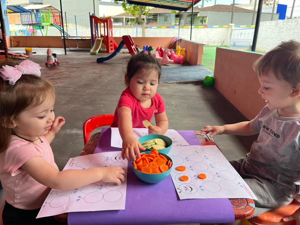Crianças brincando com cenoura e abobrinha
