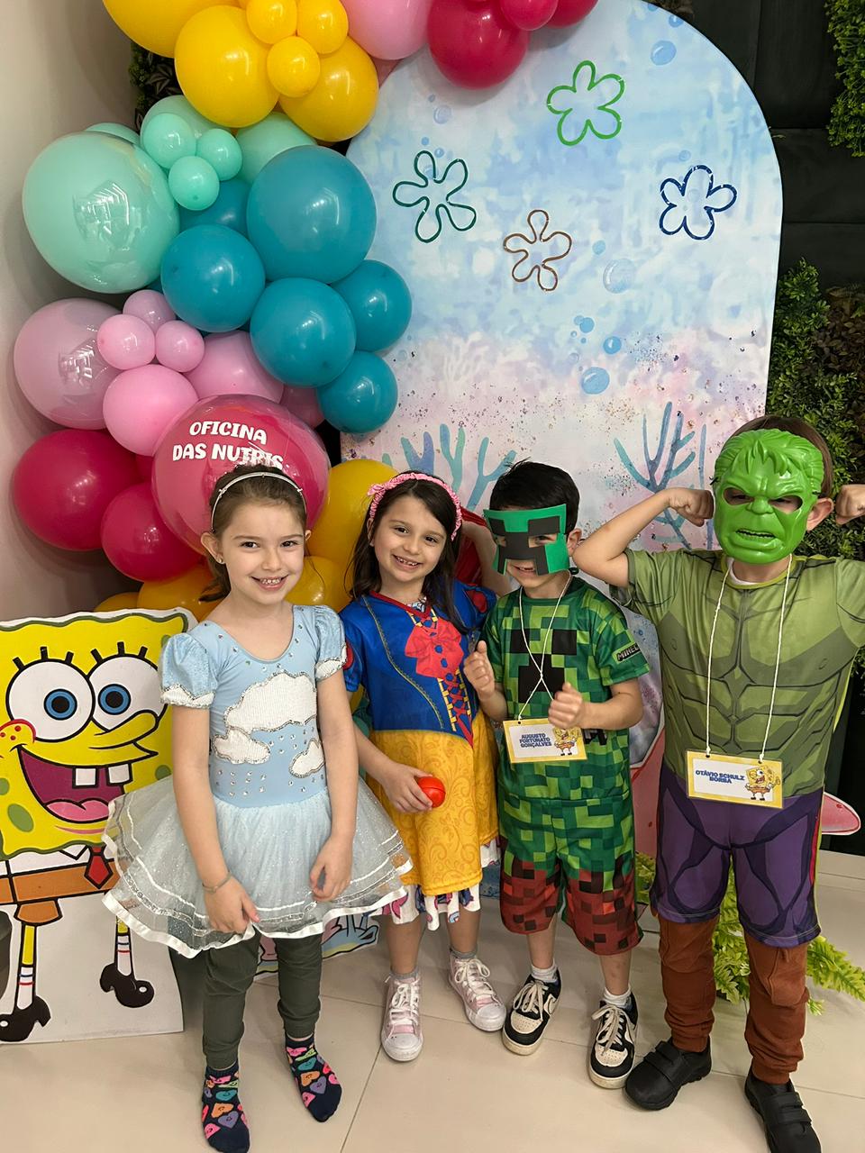 Crianças fantasiadas na frente do painel do Bob Esponja