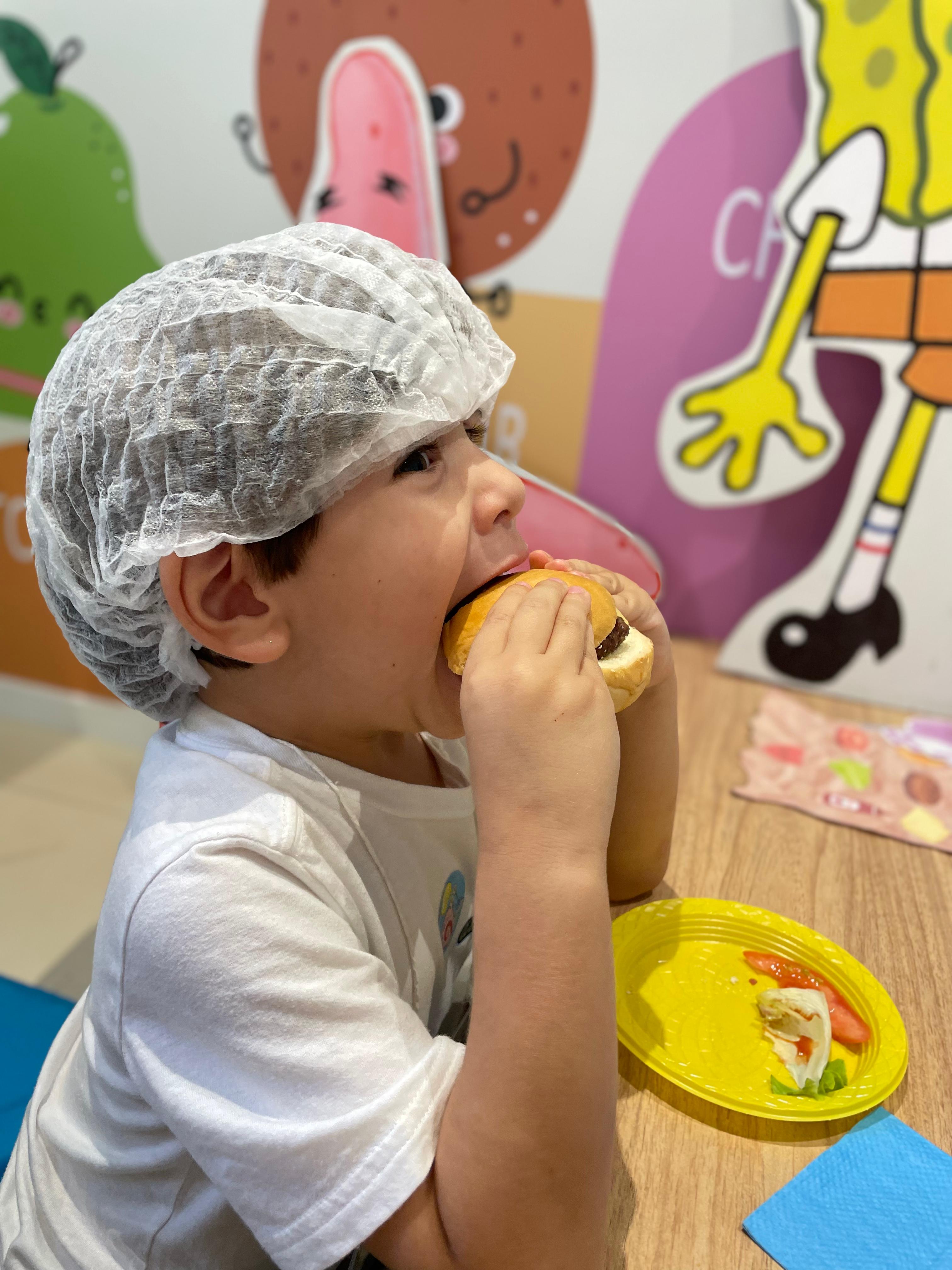 Criança posando para foto com hambúrguer na mão