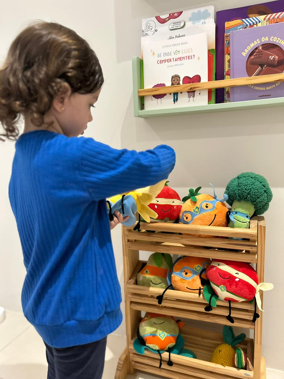 Criança brincando com frutas e legumes de pelúcia